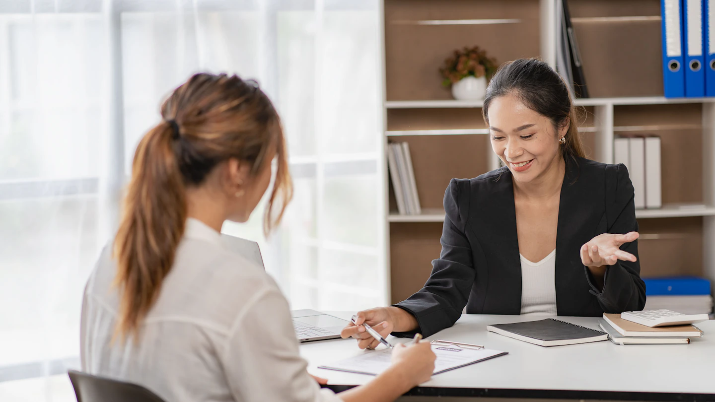 HR adviser walking a client through a document at a desk