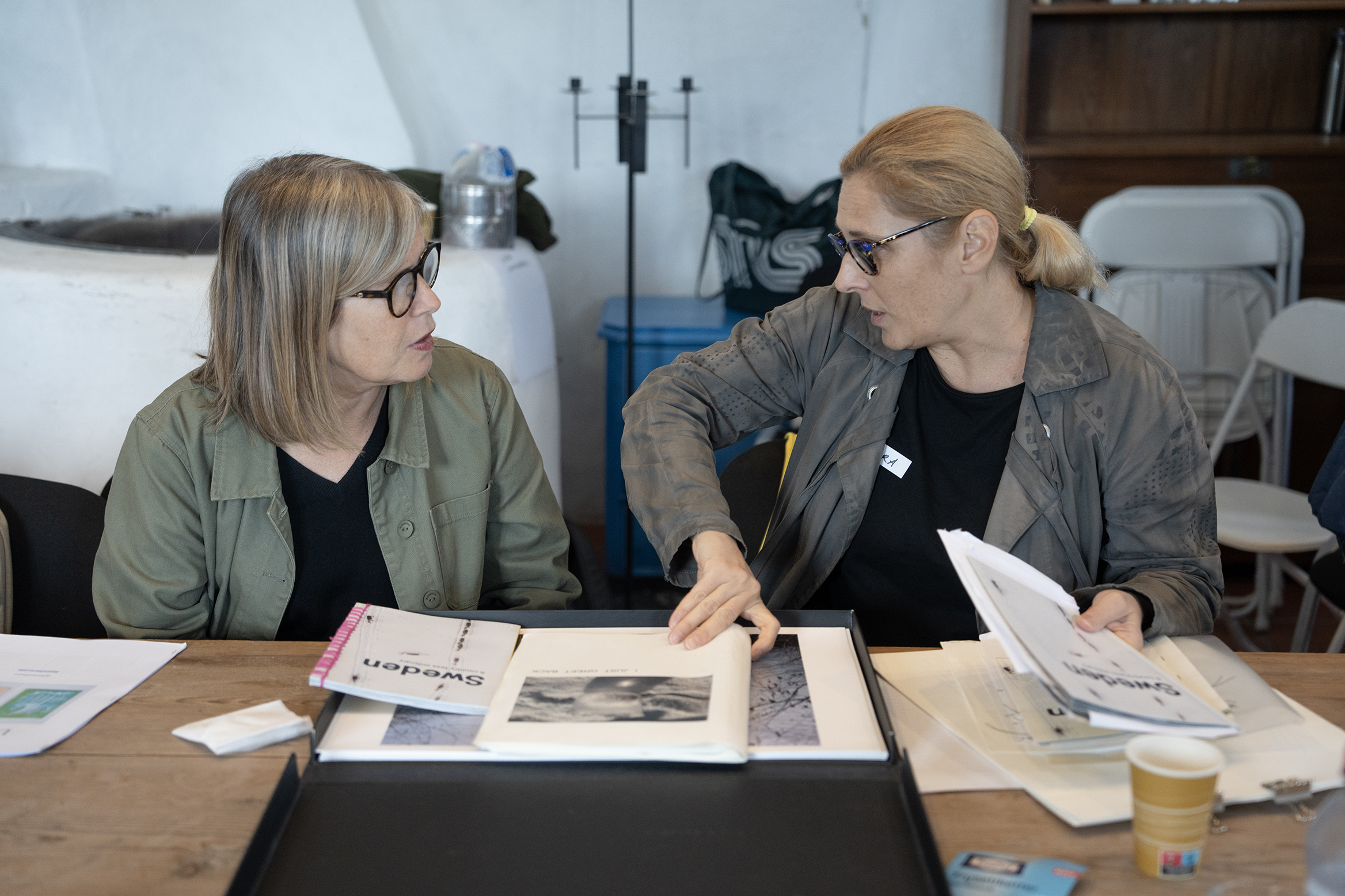 En kvinna visar porrtfolio och pratar med annan kvinna.