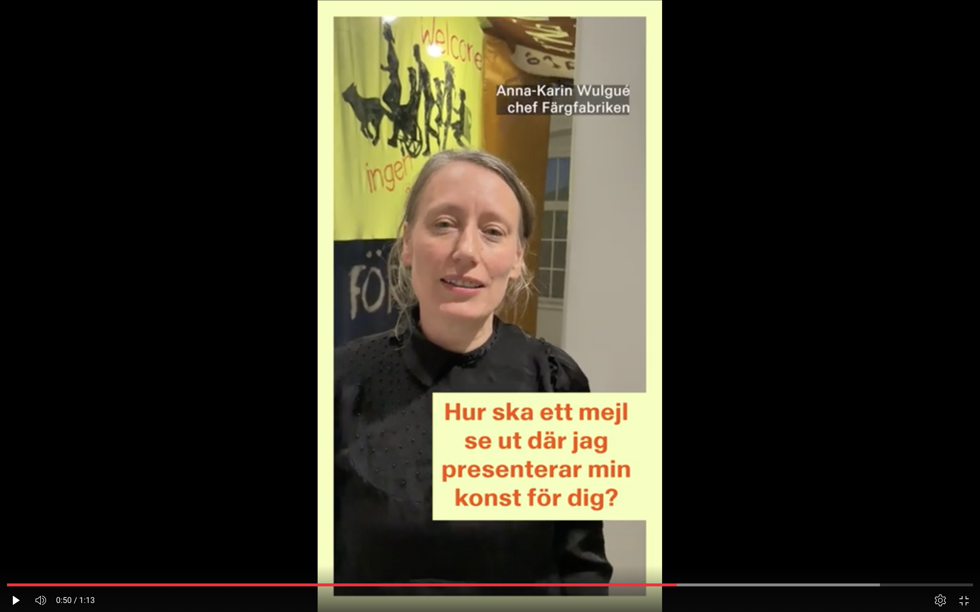 Kvinna tittar in i kameran, omgiven av färgglad konstinstallation