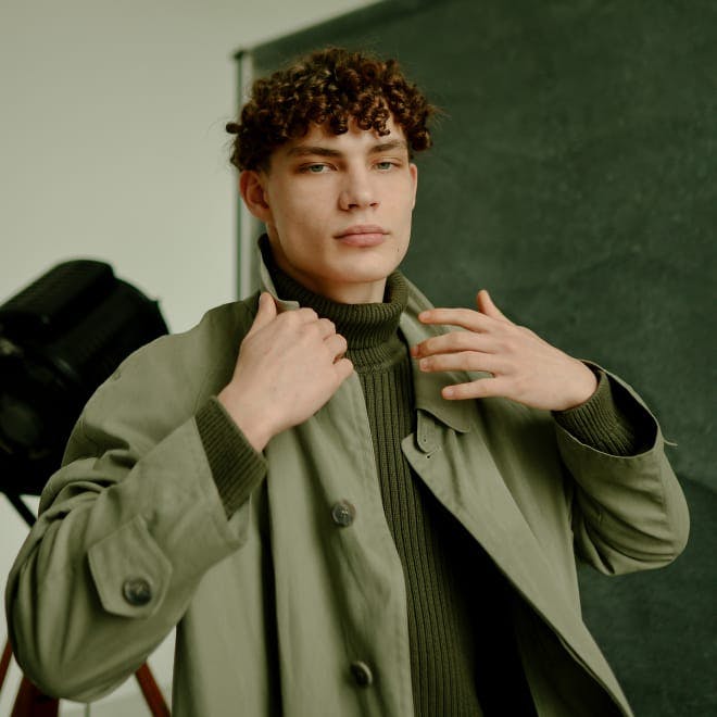 Man with curly hair in a green jacket