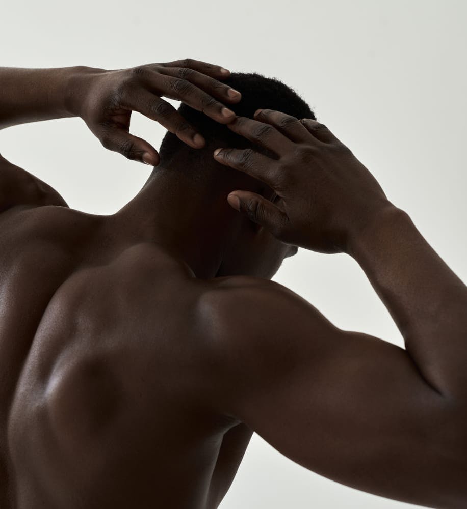 view of man's muscled back with his hands behind his head