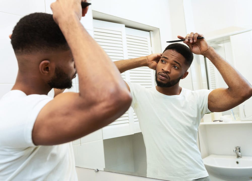 Black man combing hair in mirror