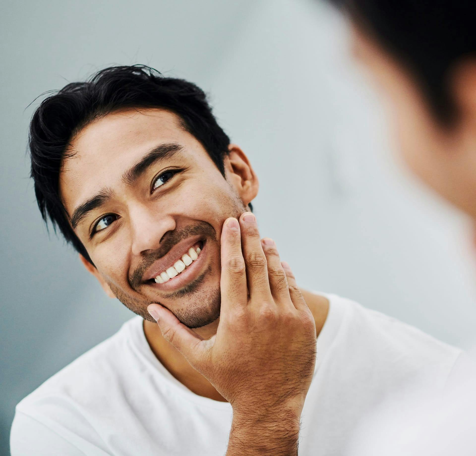 man looking at face in the mirror