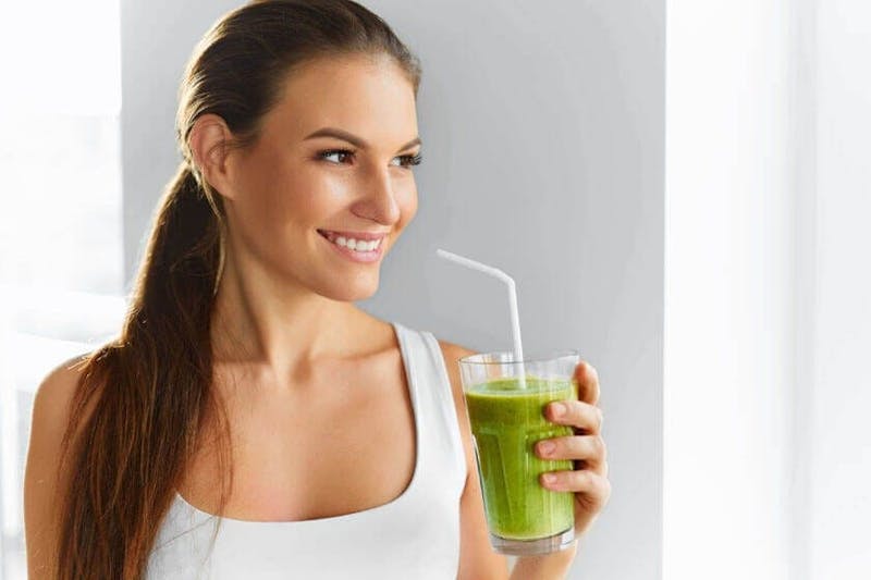woman drinking a green juice