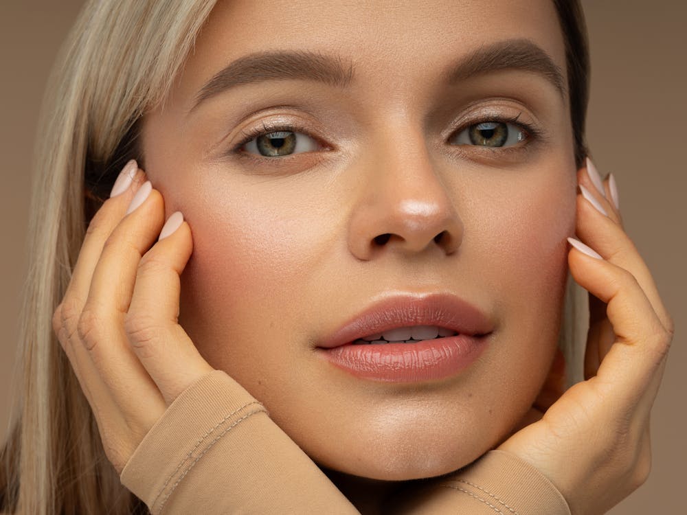 Woman looks seductively at the camera with hands on her face. Her firm and smooth skin show the potential results of IgniteRF in Boston with Neem