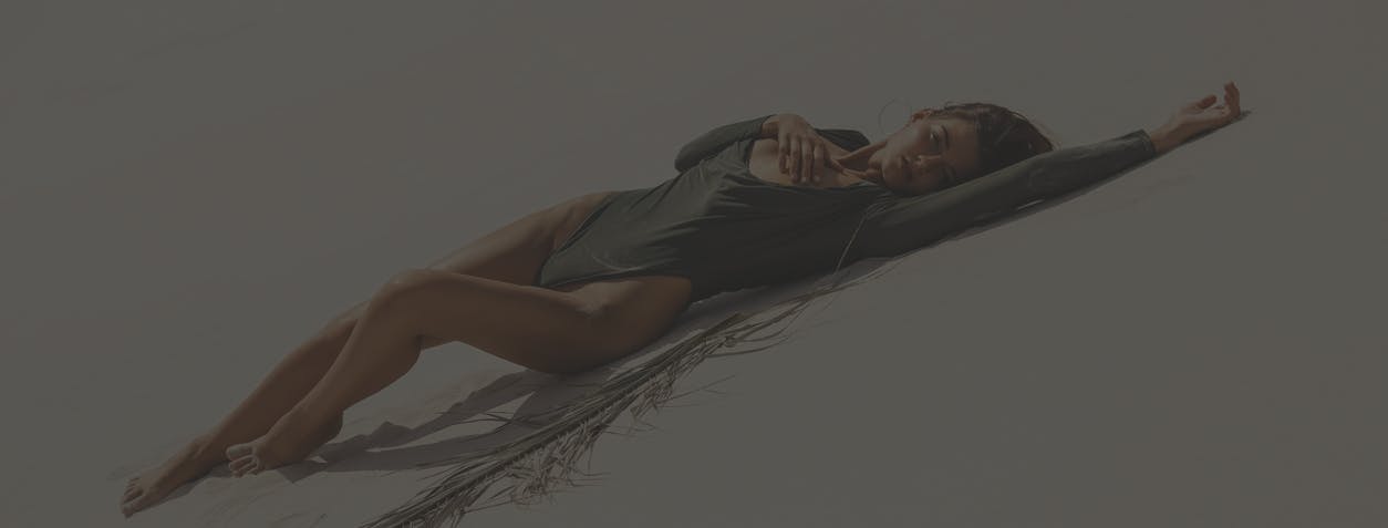 Woman laying on sand in a swimsuit. Her firm and smooth skin show the potential results of peptide therapy X in Boston with Neem