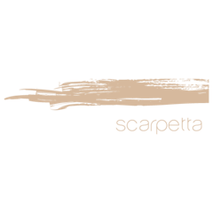 A beige paintbrush stroke is displayed above the word "scarpetta" written in lowercase, thin, light beige letters on a white background.