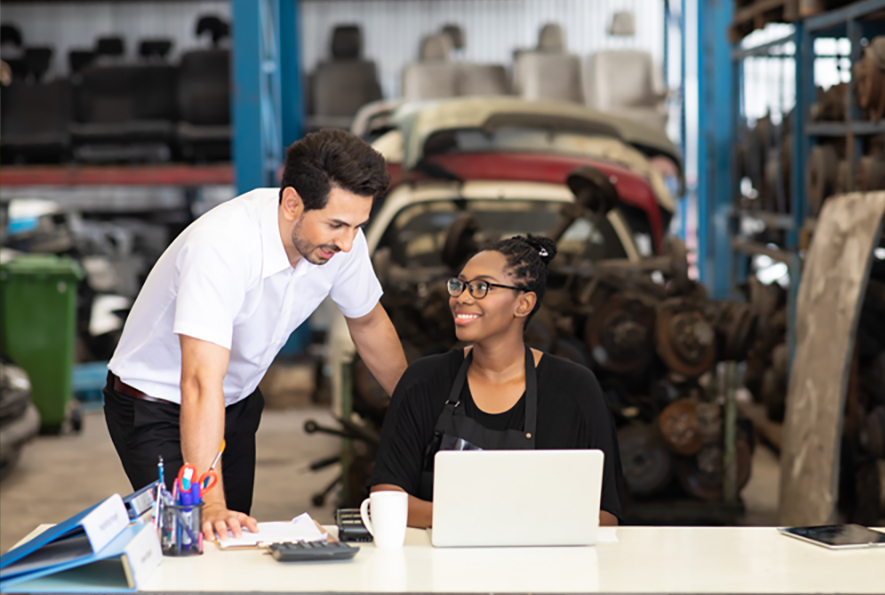 work colleagues looking at a laptop in a car parts warehouse