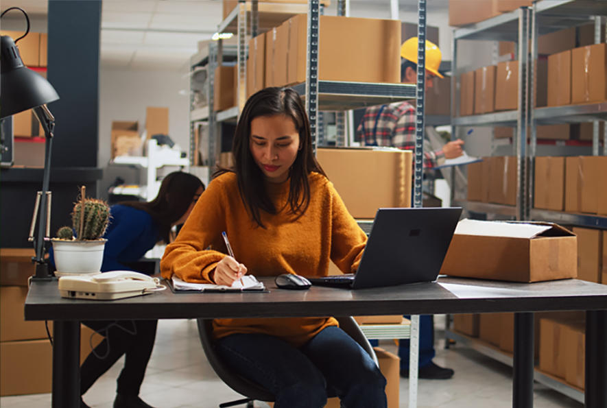 Woman writing on a notepad in a warehouse