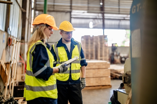 Man and woman wearing safety gear working in a warehouse