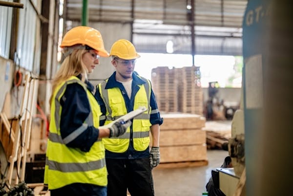 Man and woman wearing safety gear working in a warehouse