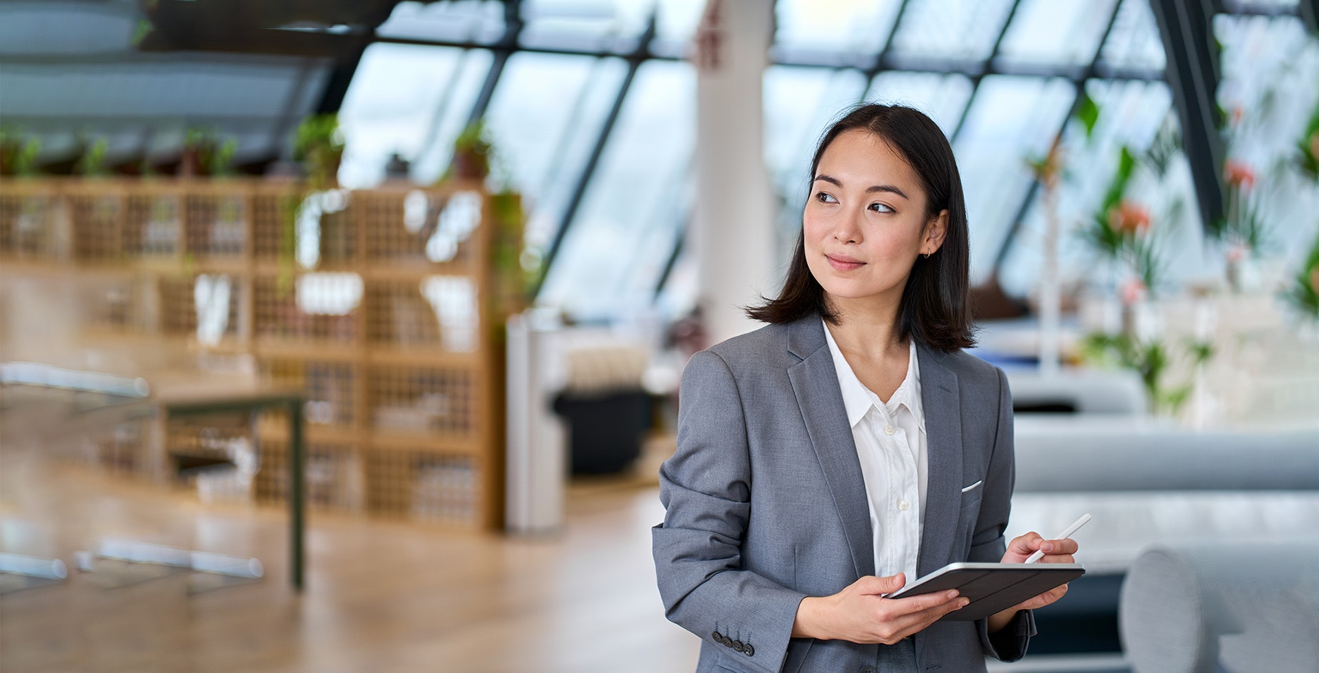 HR adviser wearing a grey suit and holding an iPad.