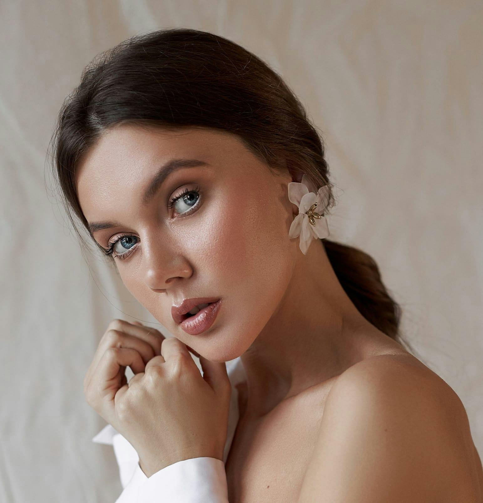 woamn with blue eyes and flower earrings