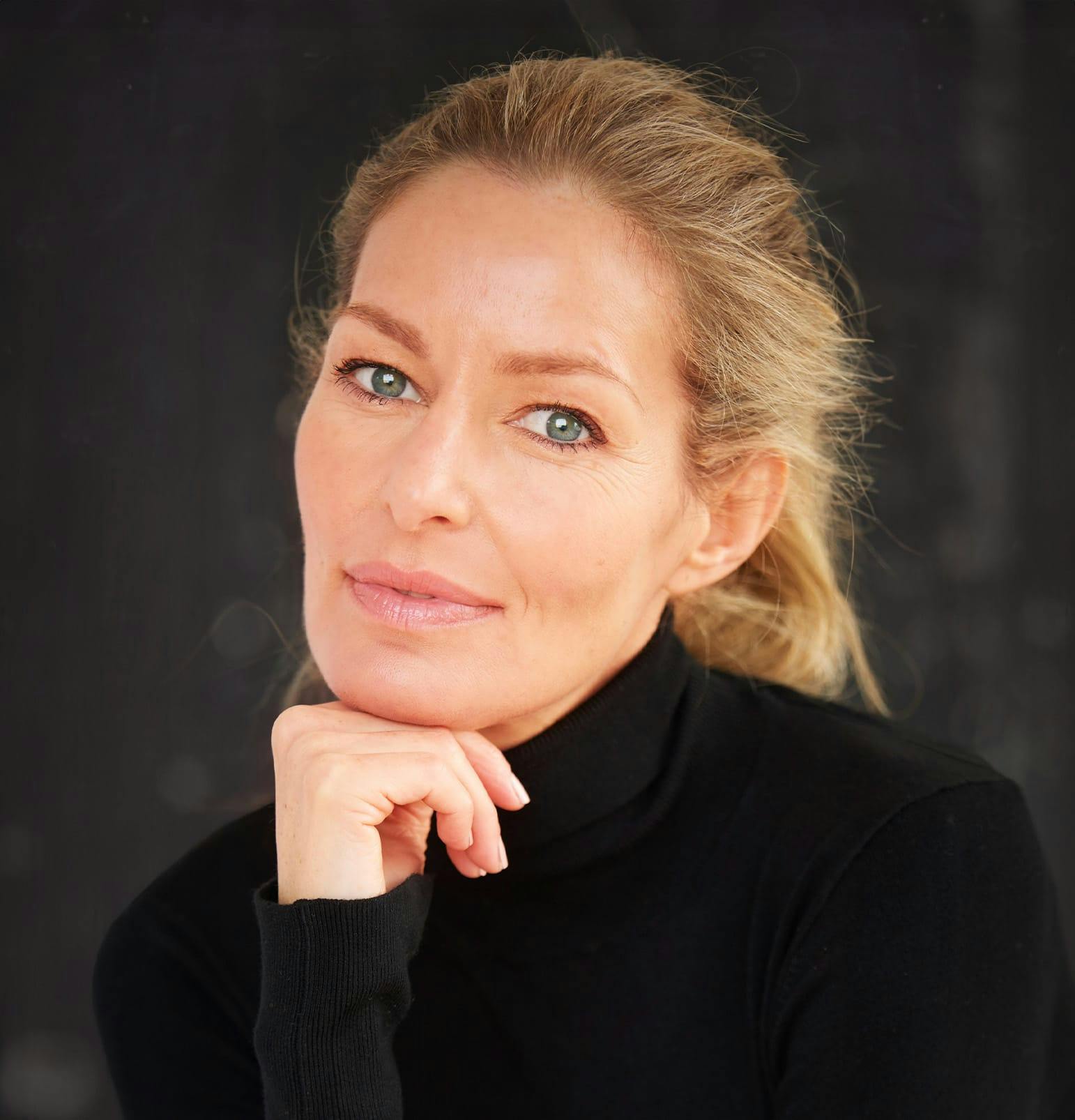 woman with blonde hair with hand under her chin