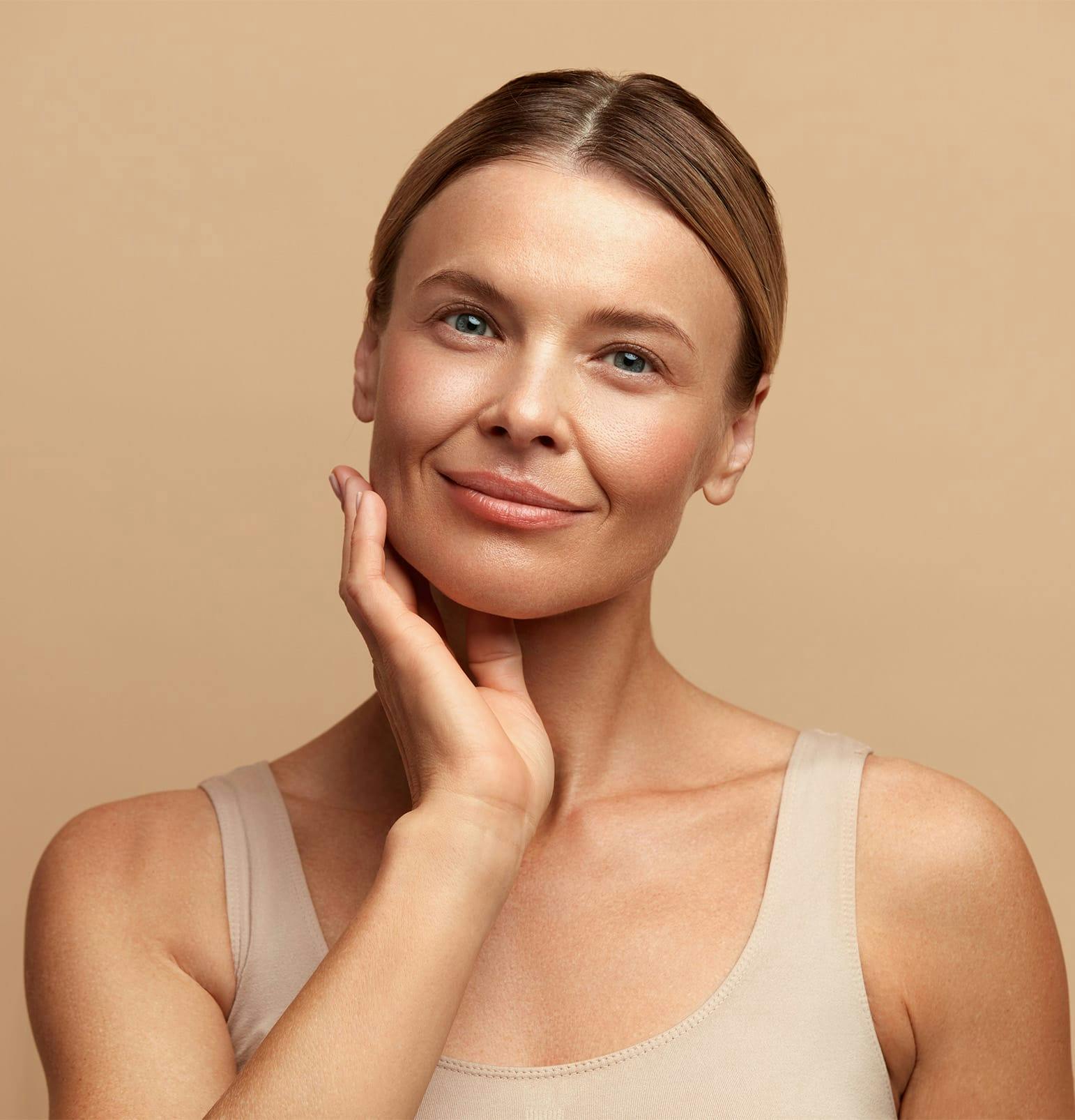 woman with hair in bun with hand touching her jaw