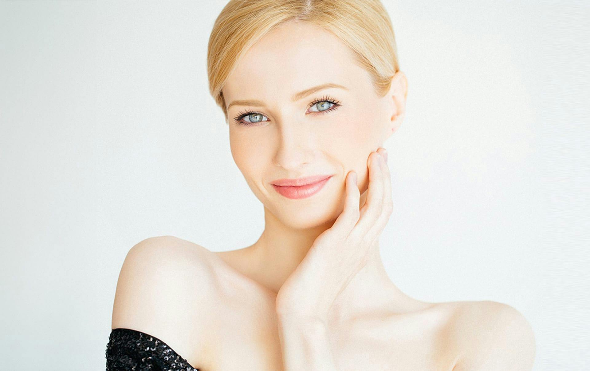 woman with hand on her face as she smiles