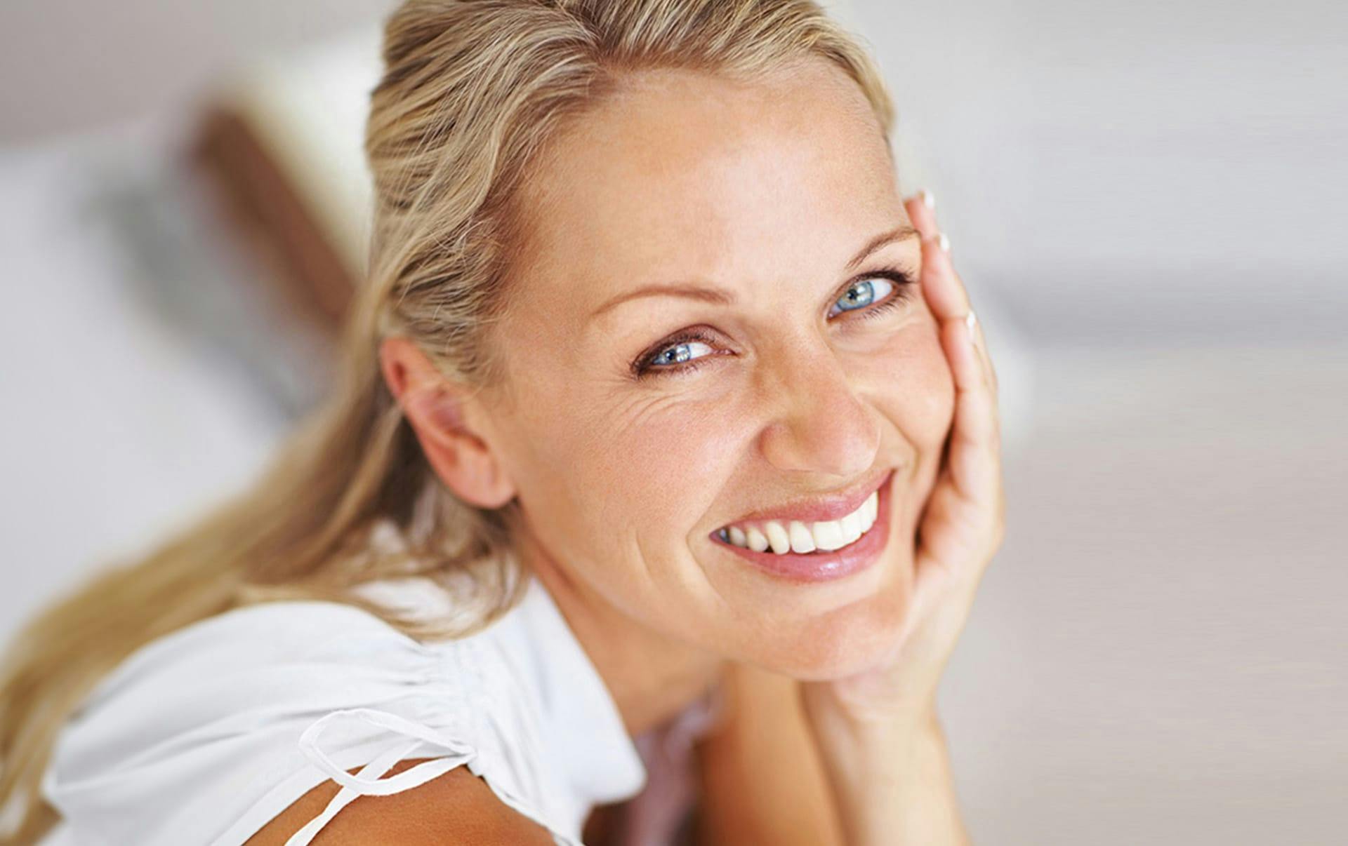 woman touching her cheek and smiling