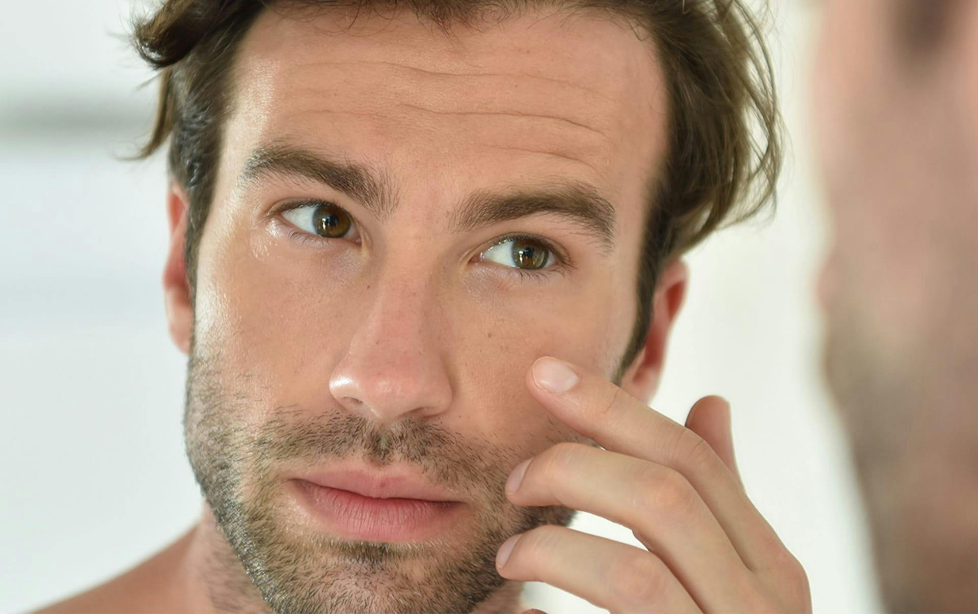 man close up about to touch his cheek with his hand