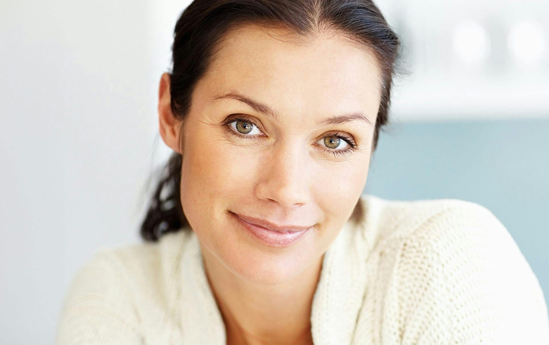 woman with ponytail smiling forward with greenish eyes