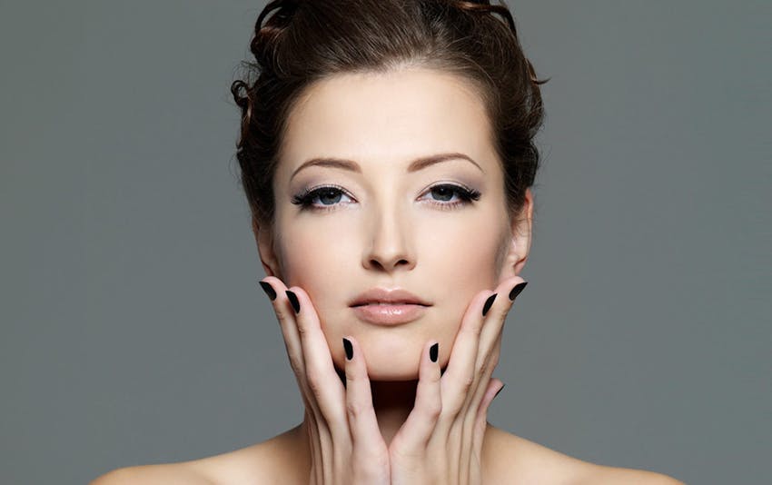 woman touching her jaw with hair tied up