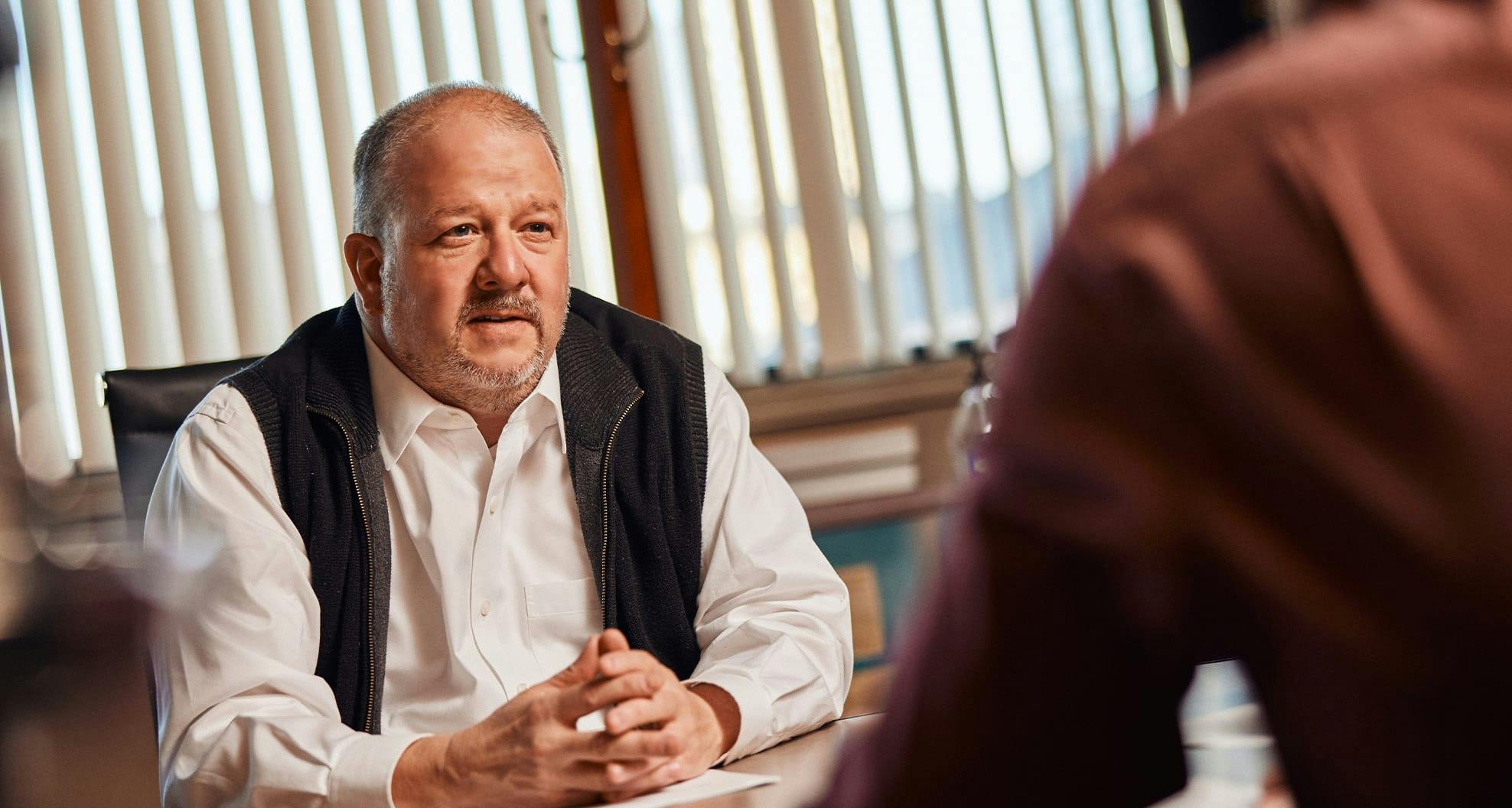 man sitting down with fingers together