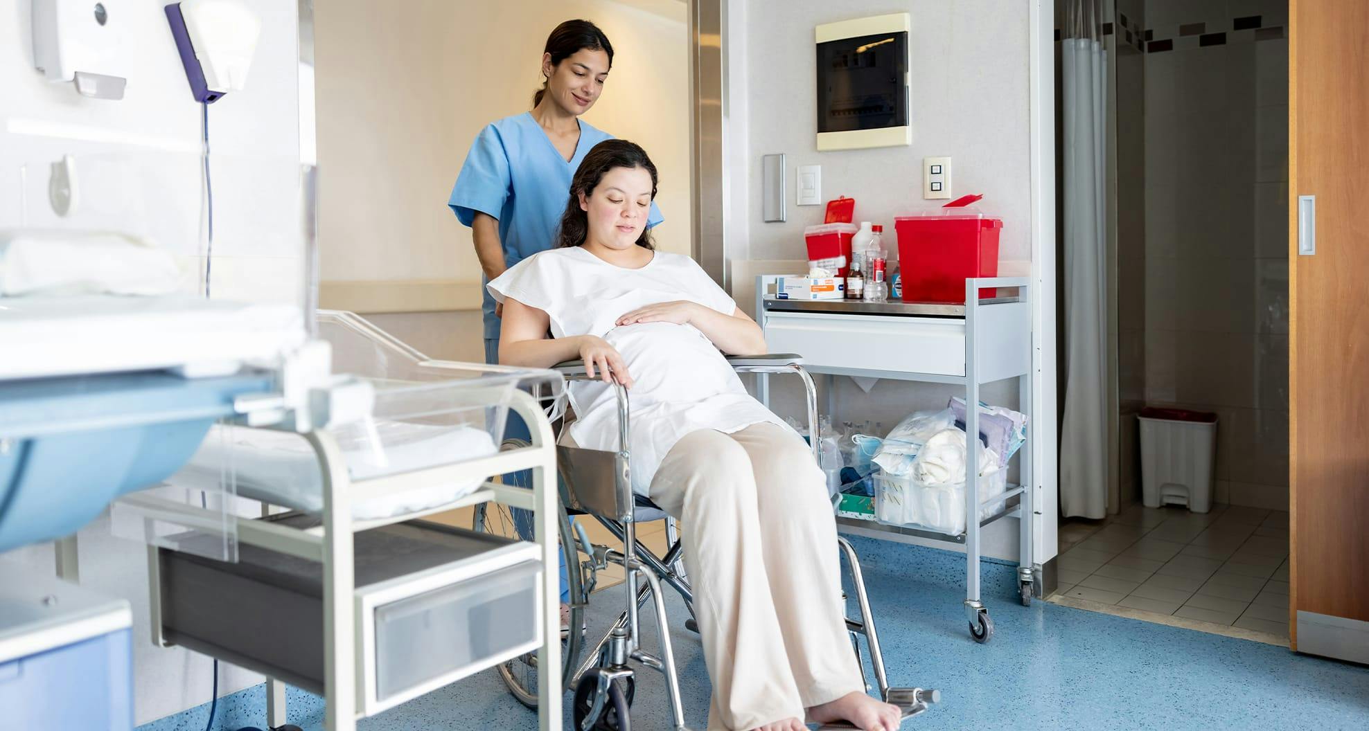 pregnant woman in wheelchair with nurse pushing the chair