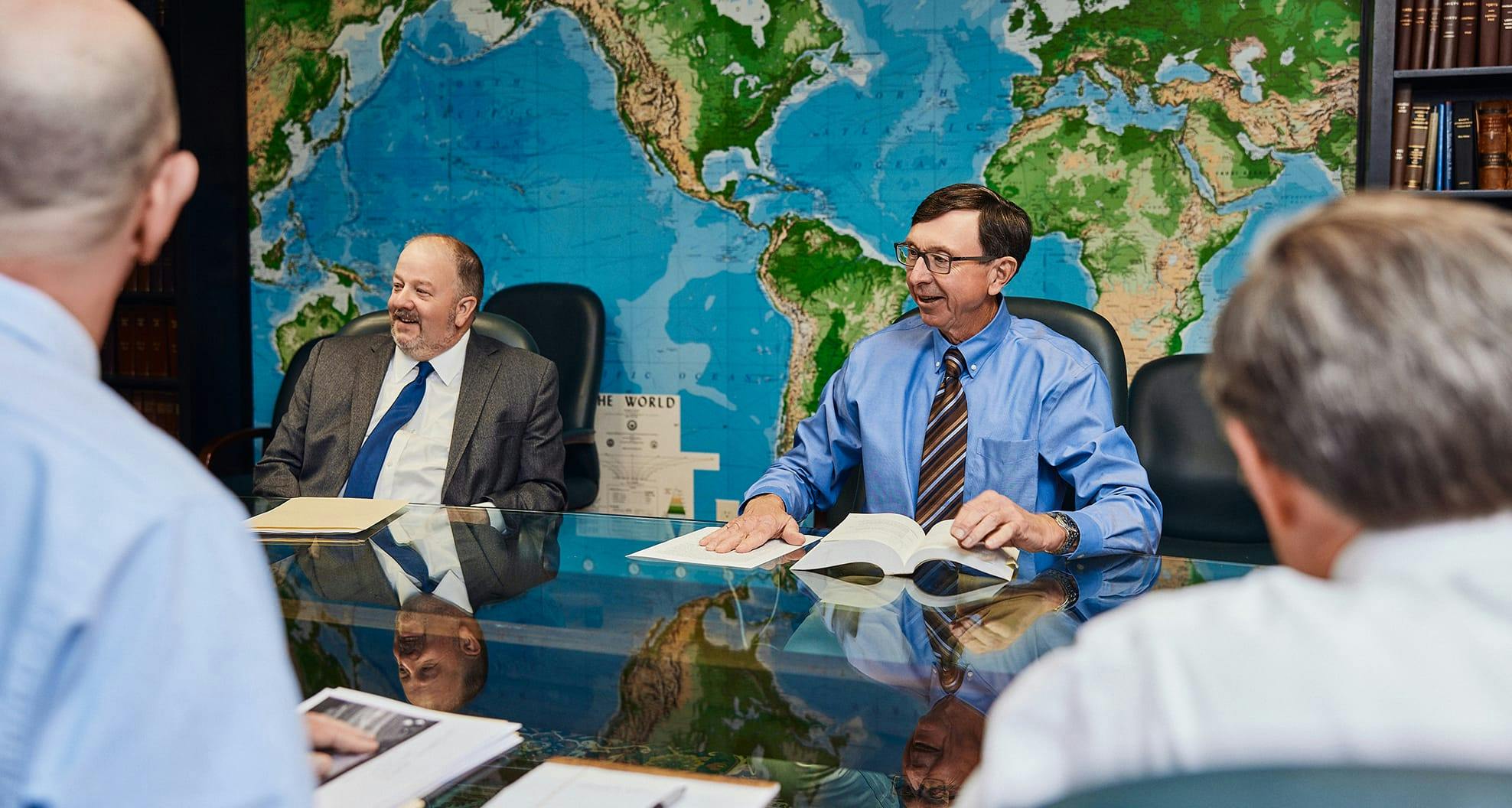 men sitting at table with world map on the wall