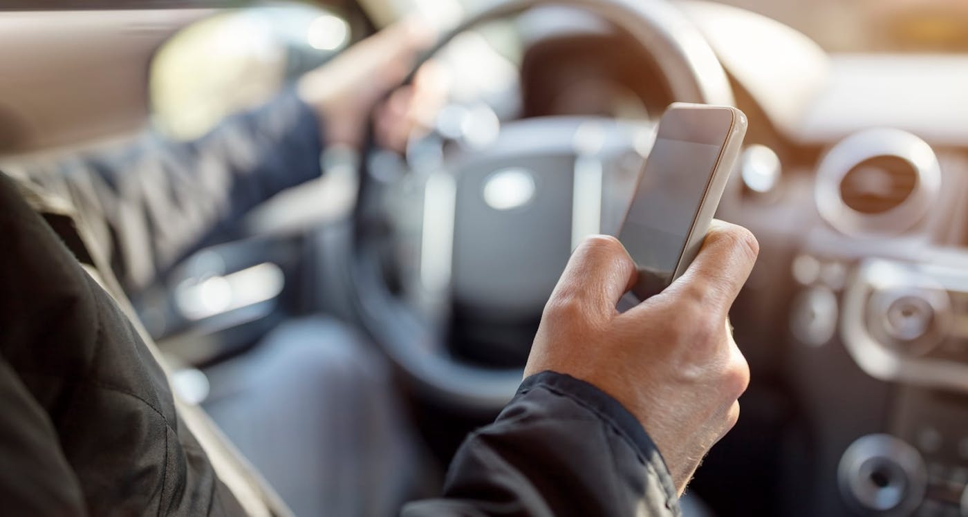 person driving and looking at phone