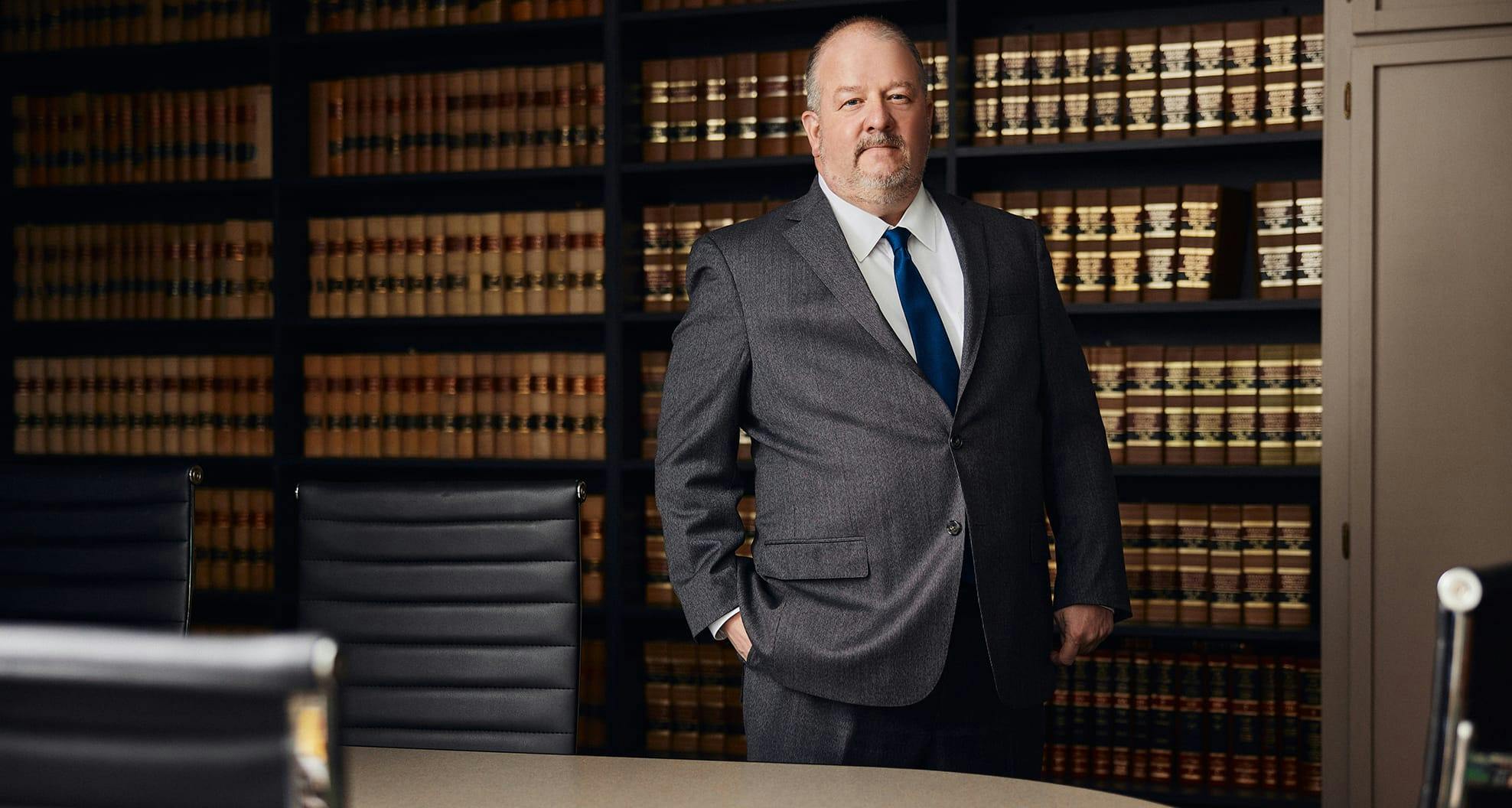 man in suit in front of bookshelf