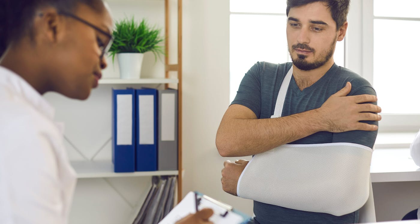 man with sling on his arm with doctor