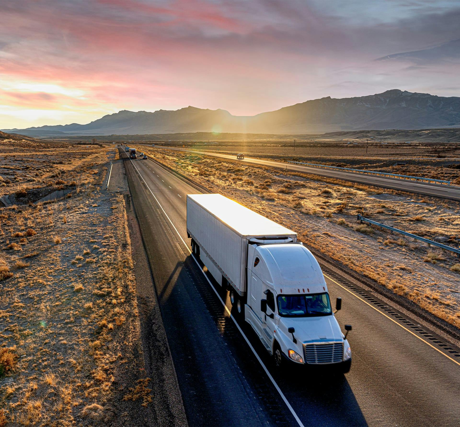 truck on long road with sunset in background