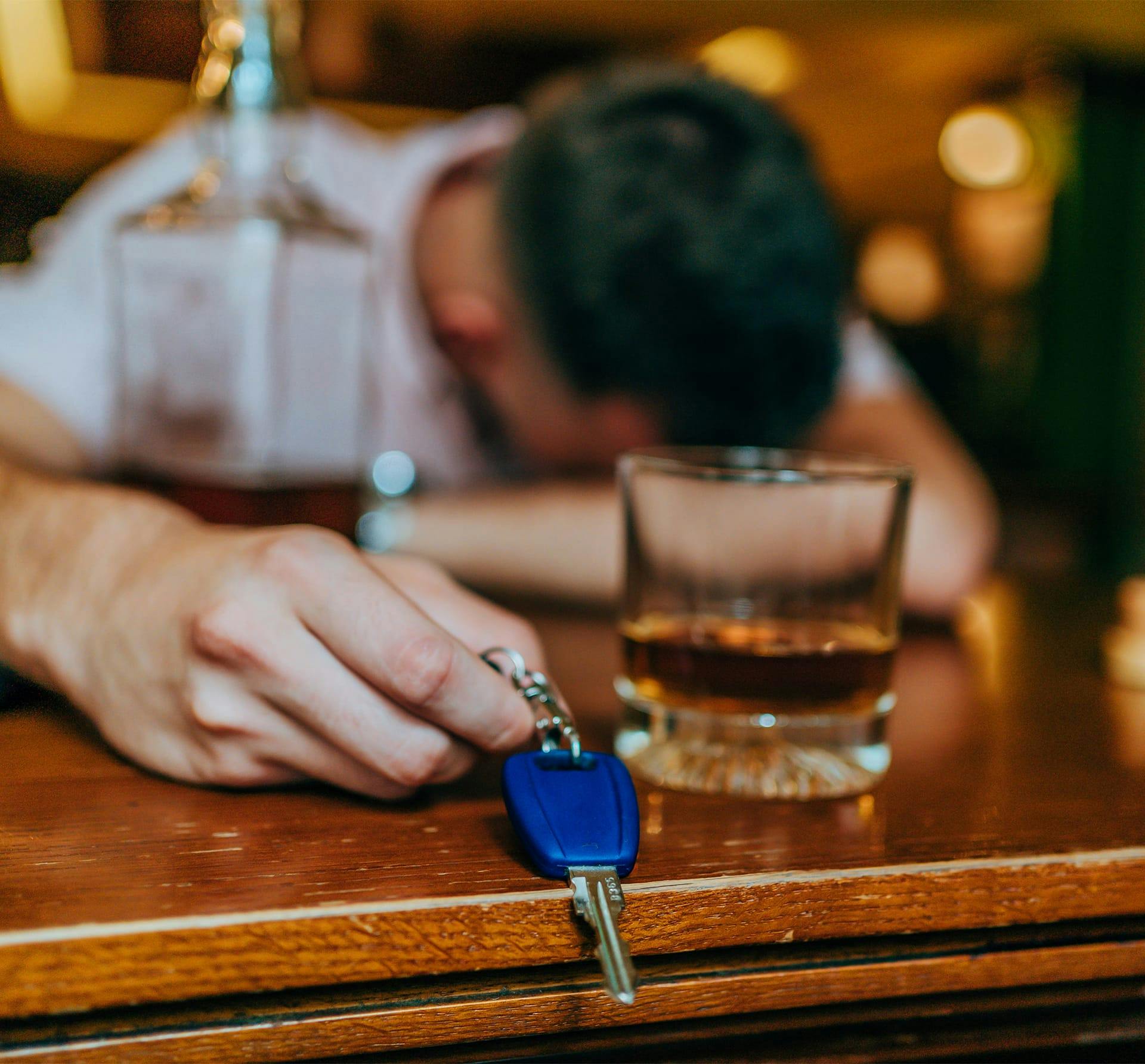 man holding keys with alcohol bottles next to him