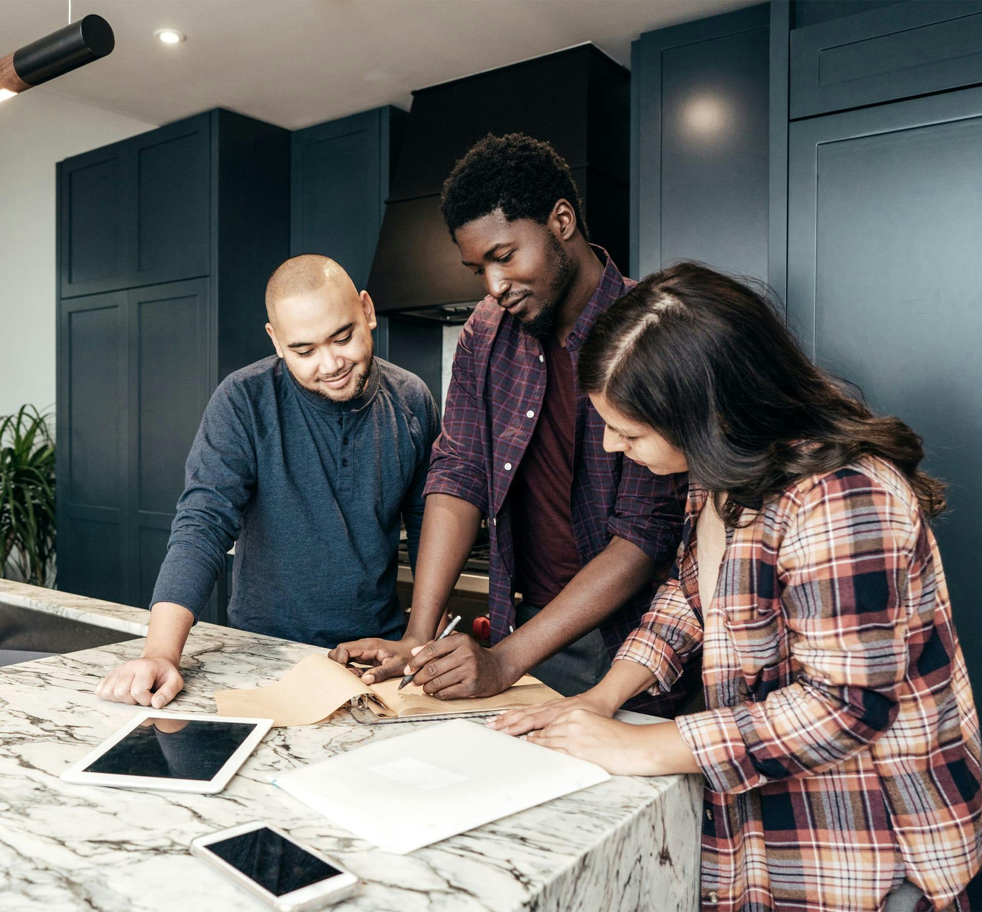 3 people in kitchen looking at paperwork