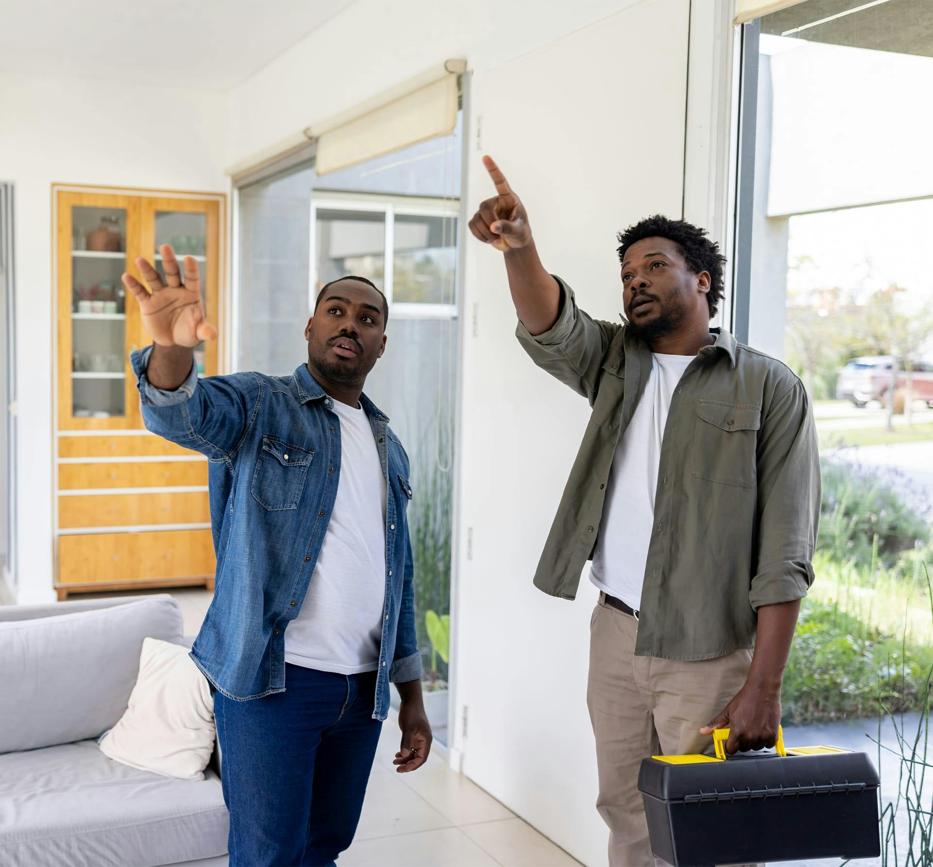 2 guys pointing up at ceiling of house
