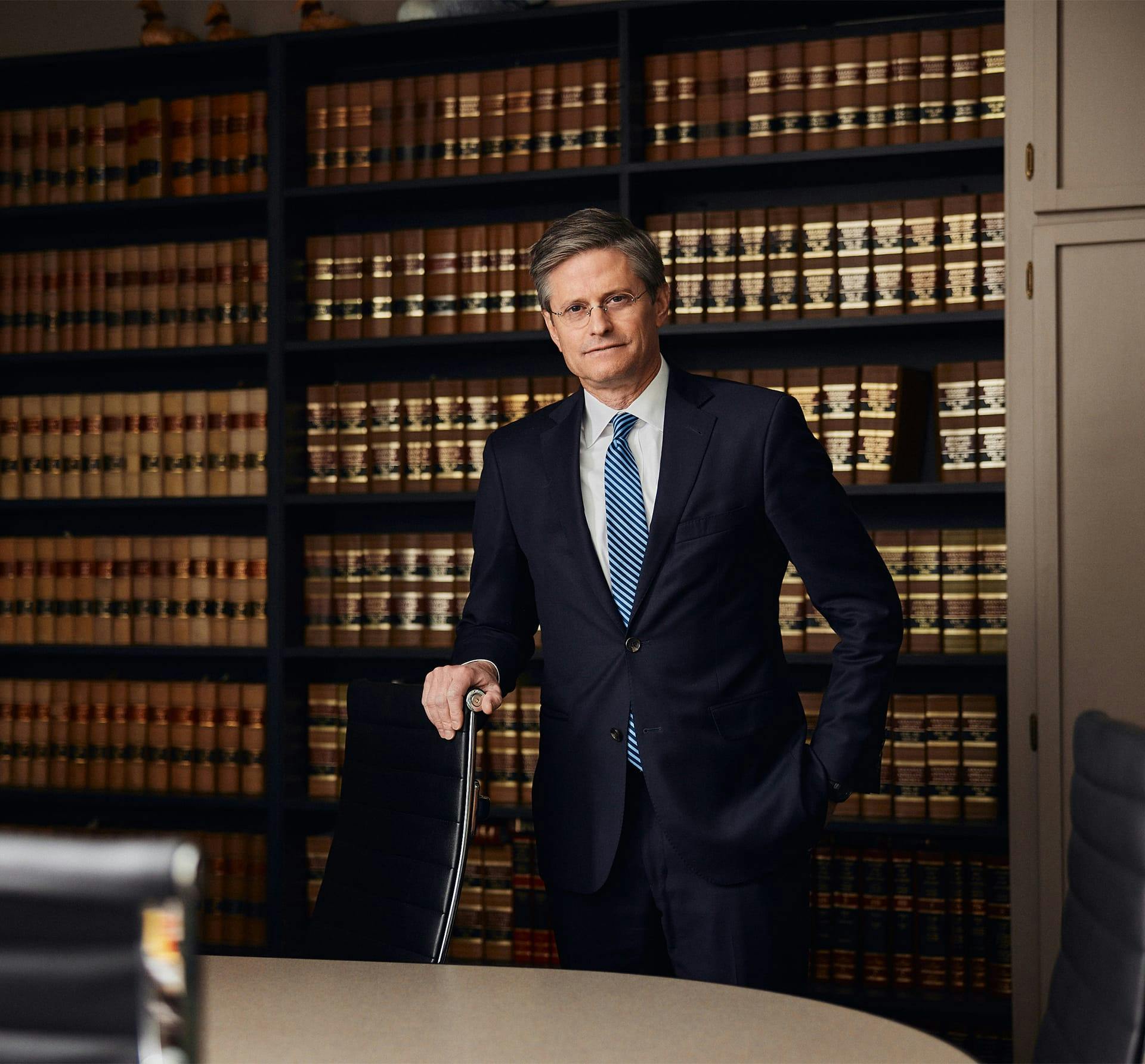 man in suit holding onto chair