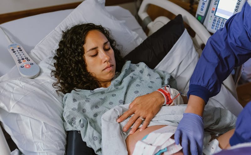 Healthcare provider examining a laboring patient in a hospital labor and delivery room.
