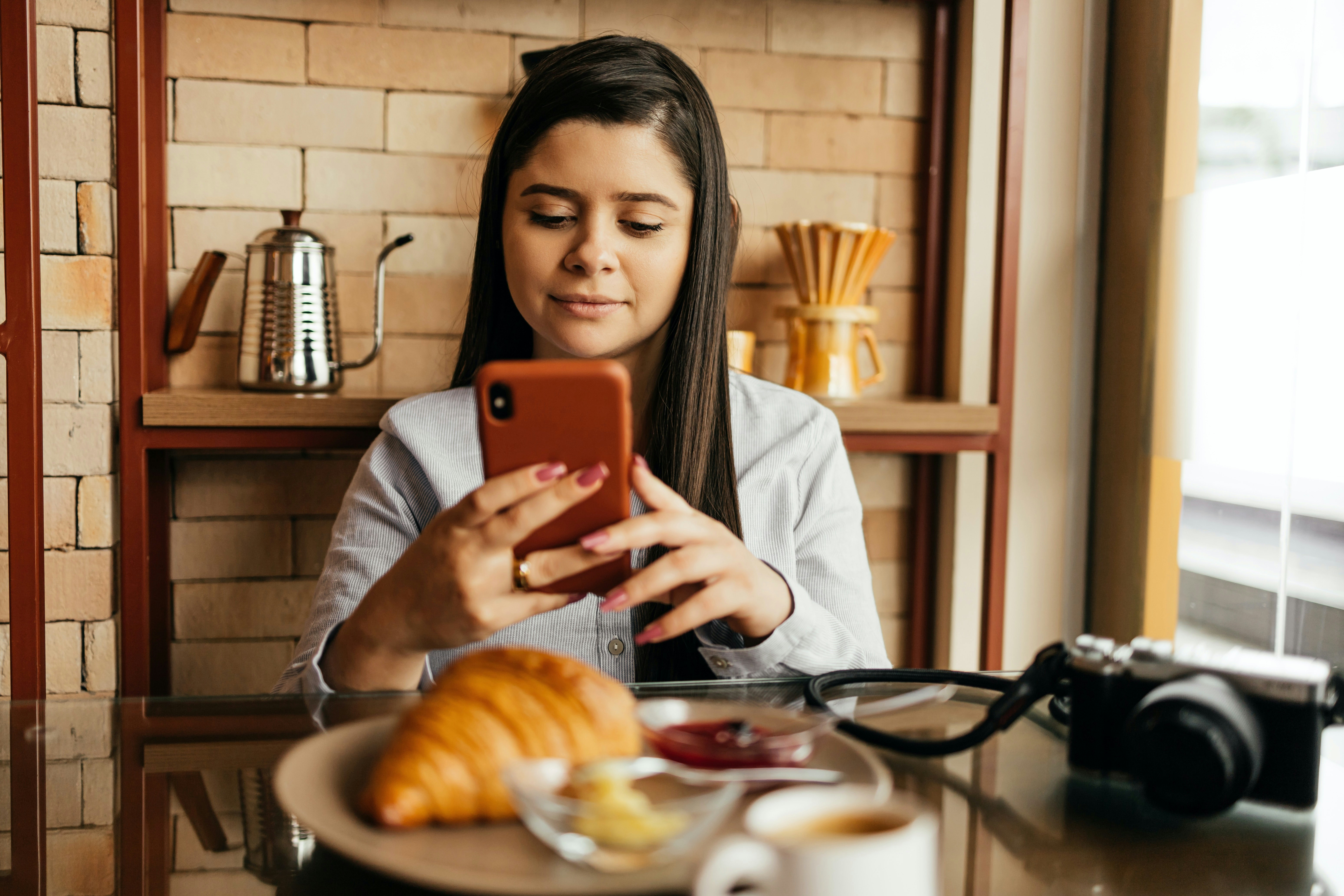 Donna che prende in foto il croissant che ha comprato con Satispay al bar