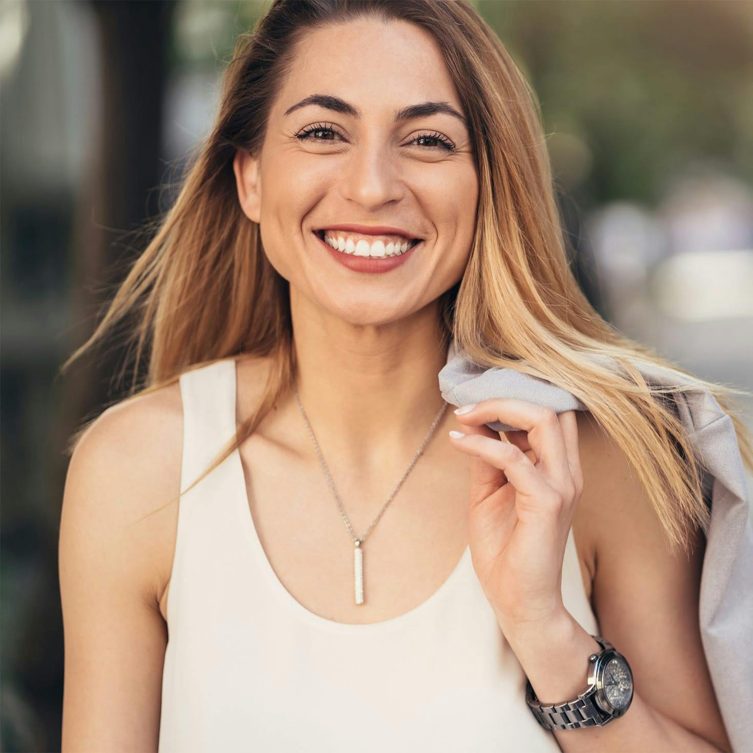 woman smiling, holding her jacket over her shoulder
