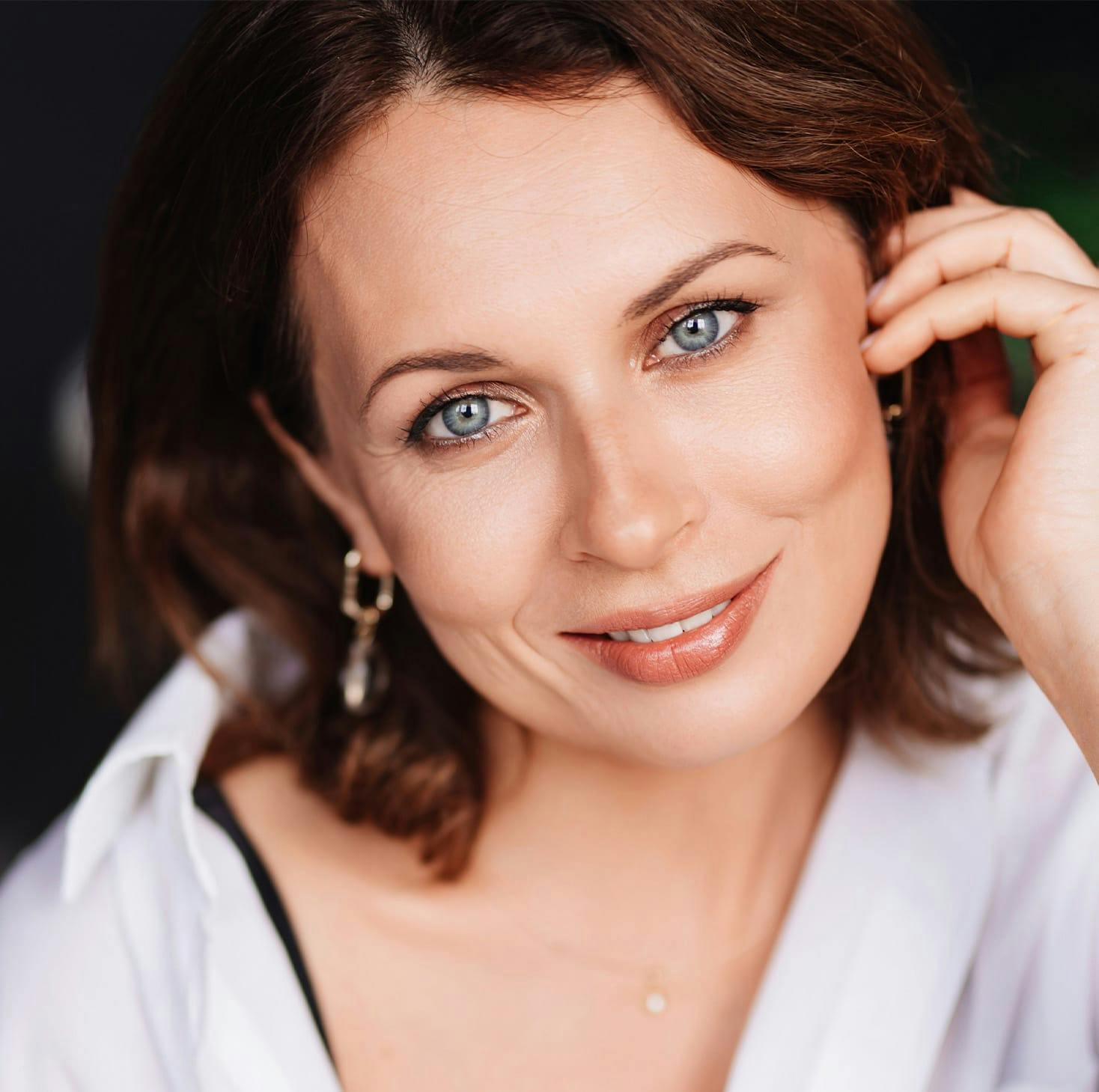 woman brushing her hair behind her ear