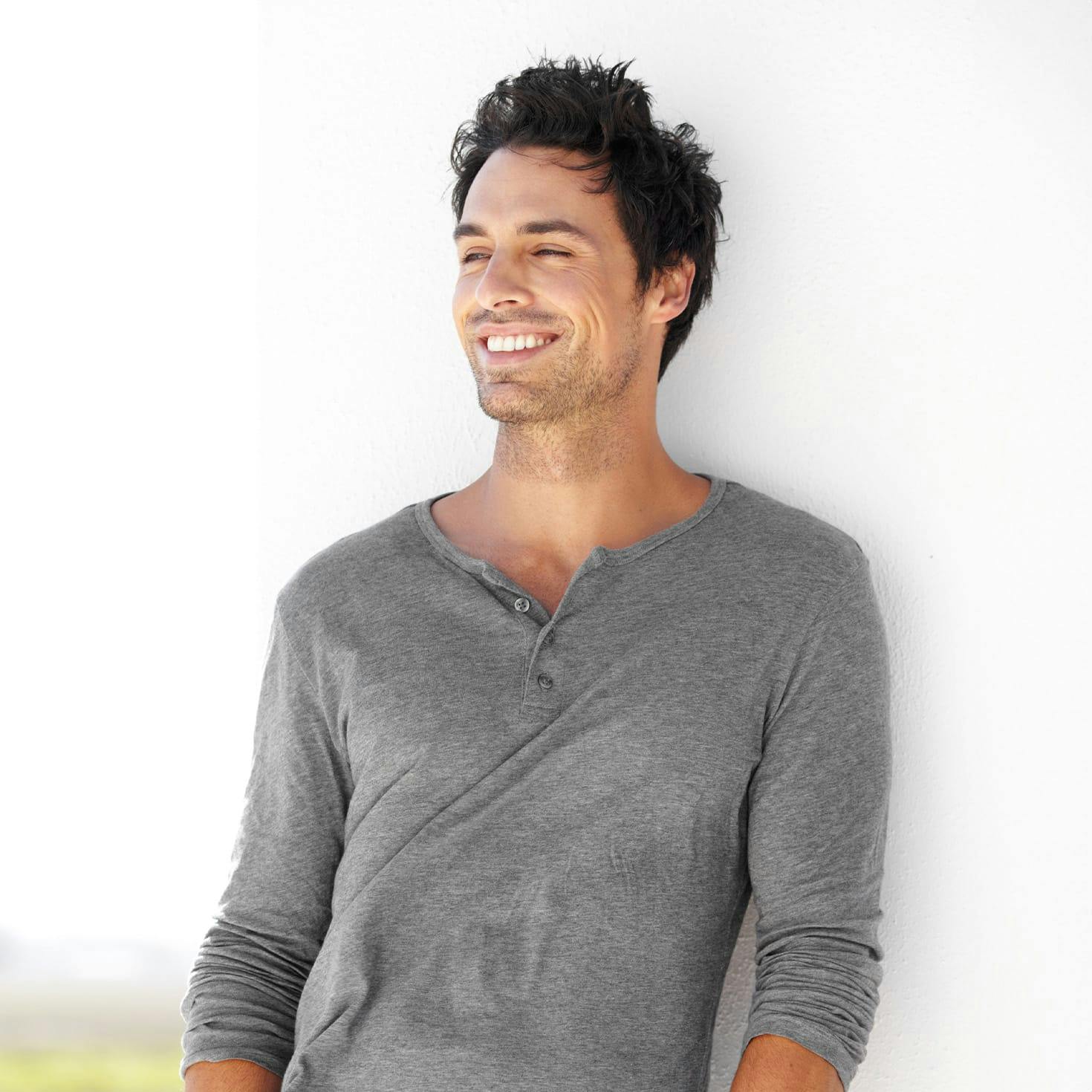 smiling man leaning against a wall