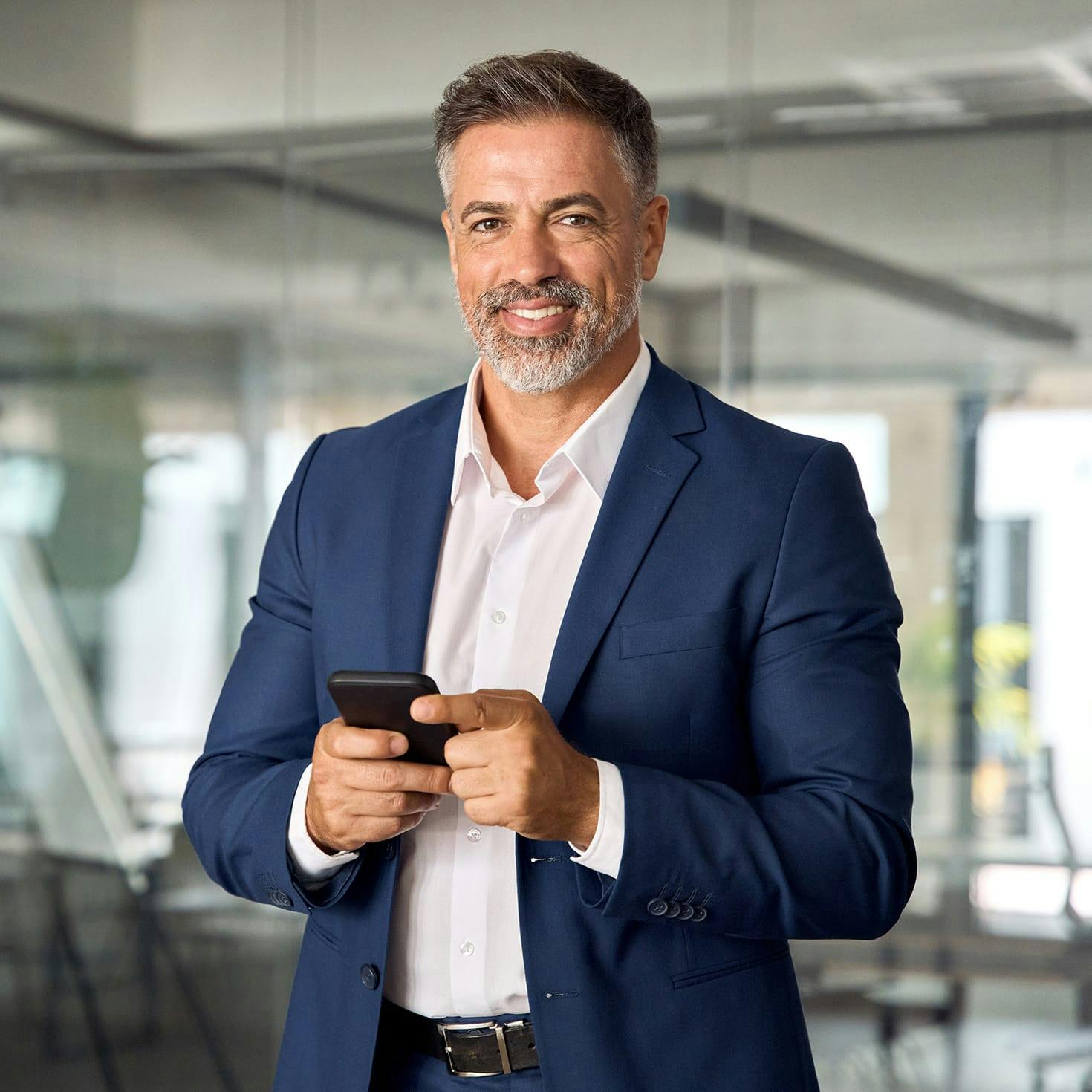older man smiling, holding a phone