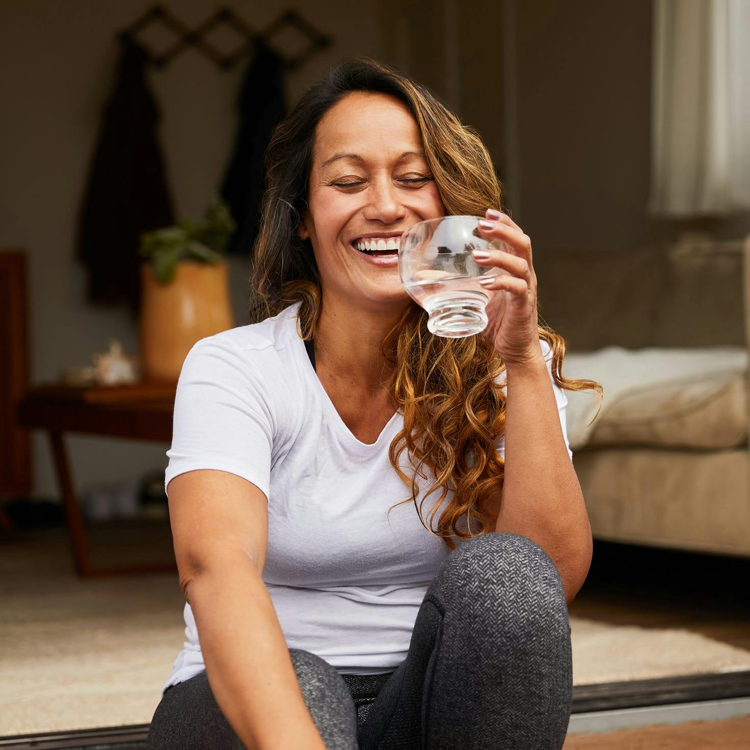 woman laughing, about to take a drink from a glass