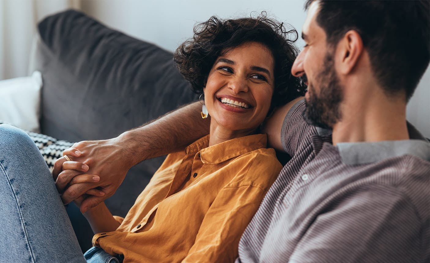 man and woman snuggling on a couch