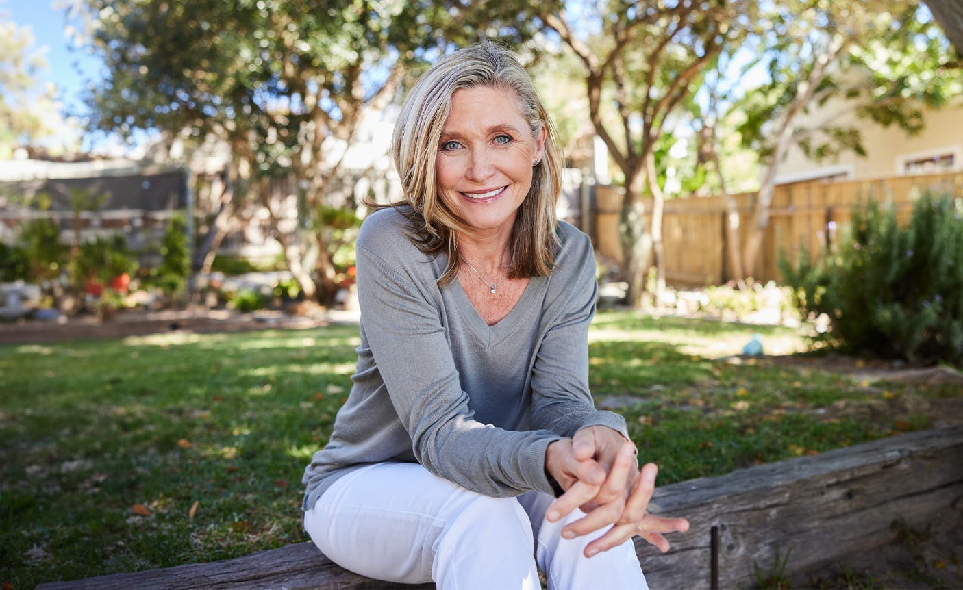 smiling woman sitting on a log