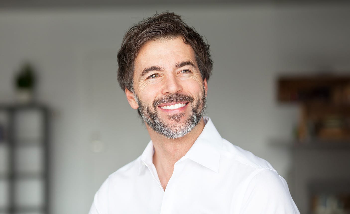An older man in white top smiling