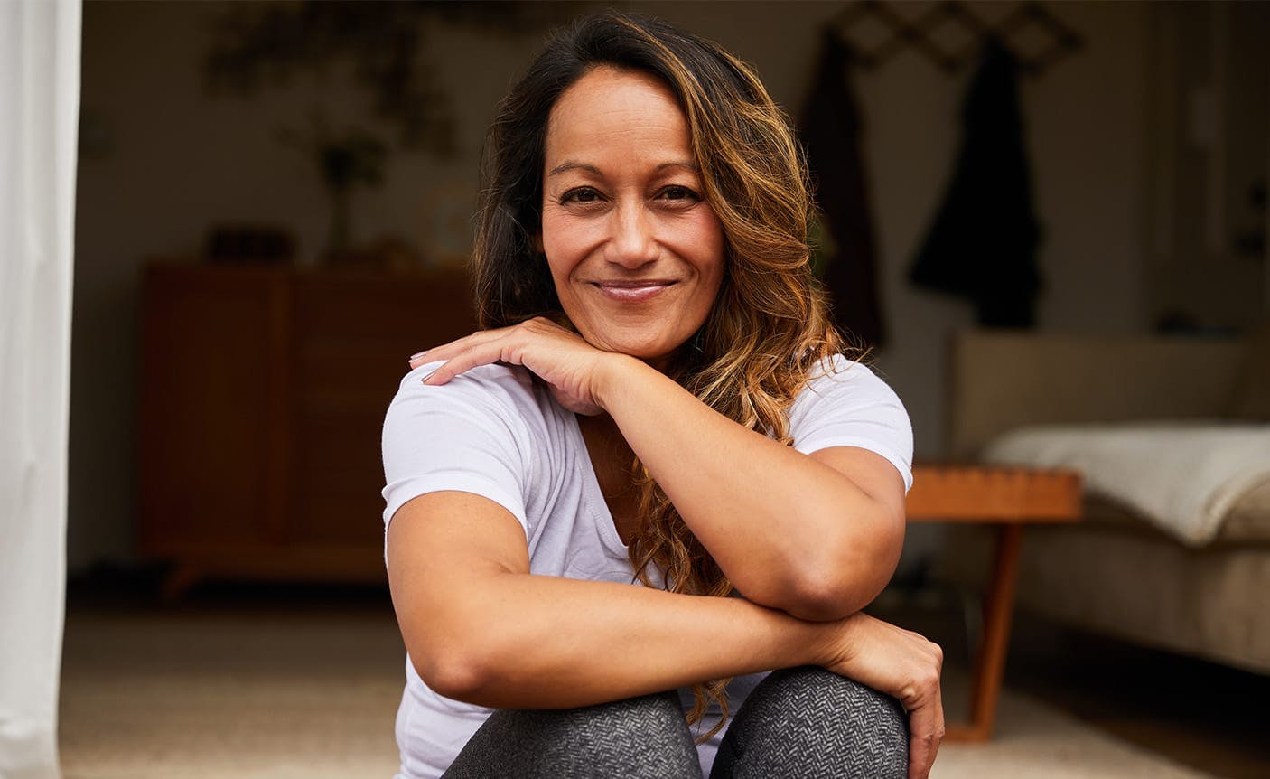 woman sitting on the ground, resting her arms on her knees