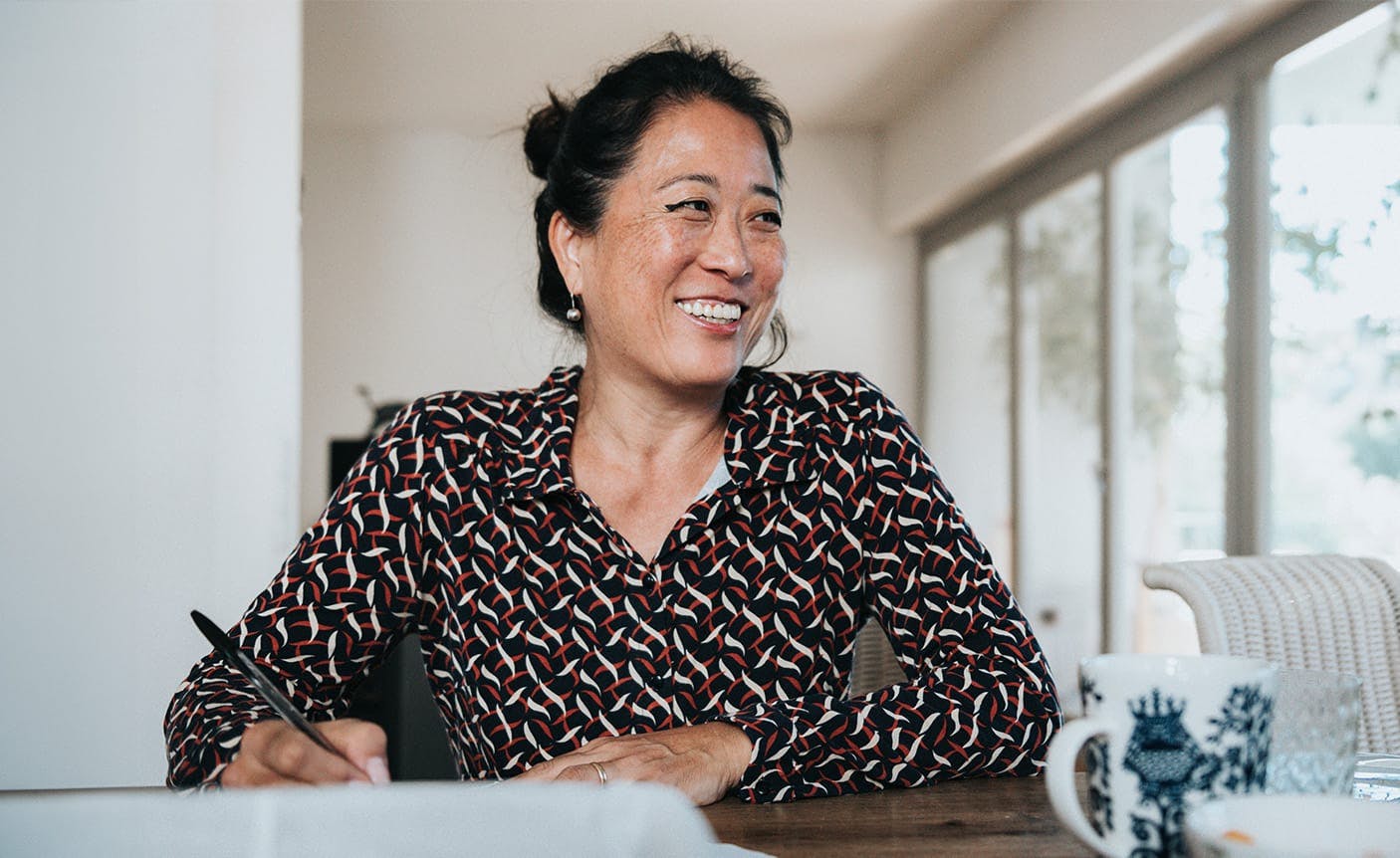 woman sitting at a table holding a pen