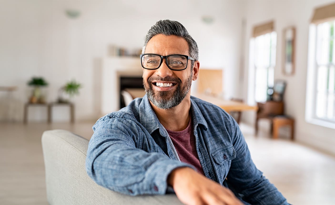 older man smiling, sitting on a couch