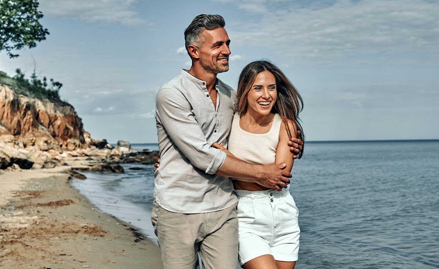 couple holding each other, walking on a beach
