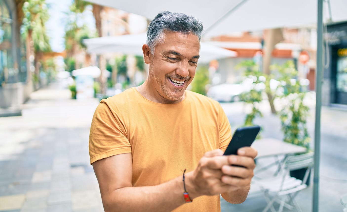 man in a yellow shirt on his phone